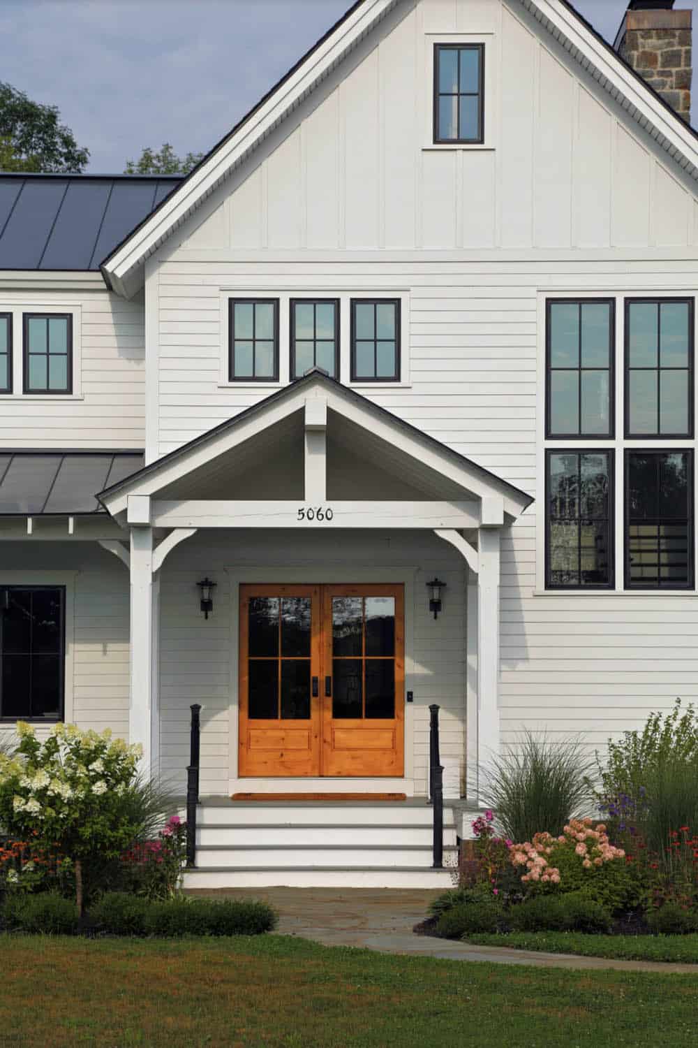 Close-up of farmhouse entrance with natural wood double doors and gabled portico