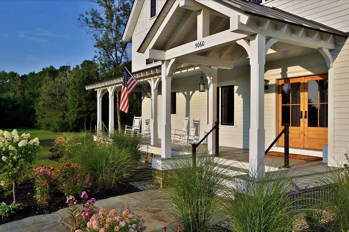 Covered front porch with white rocking chairs, timber columns, and garden landscaping