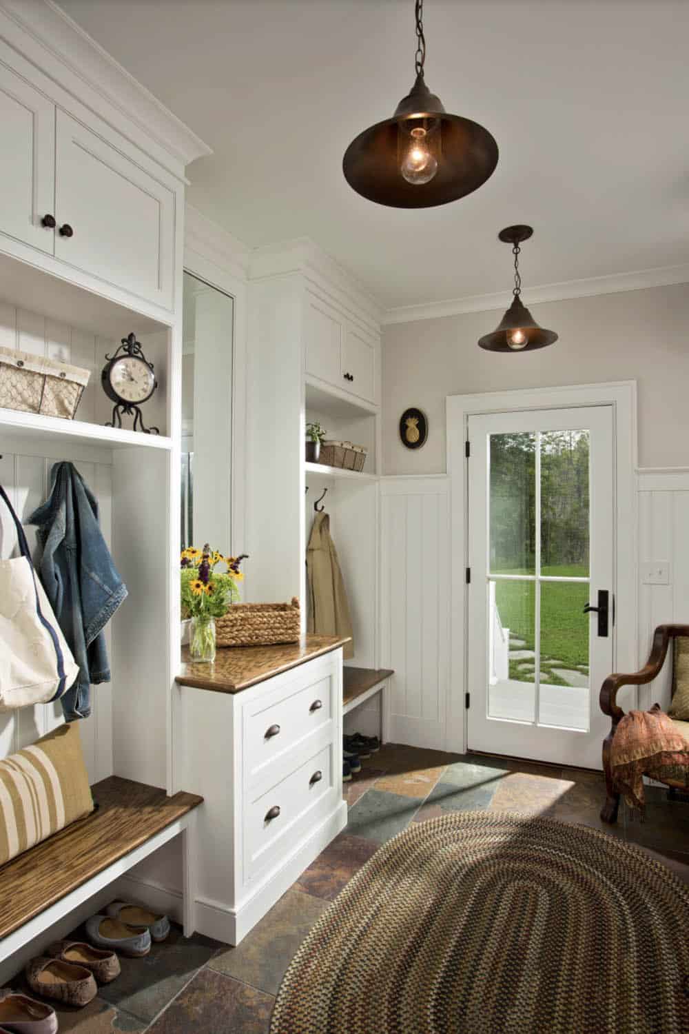 Mudroom with built-in lockers, wood bench, slate tile floor, and barn pendant lights