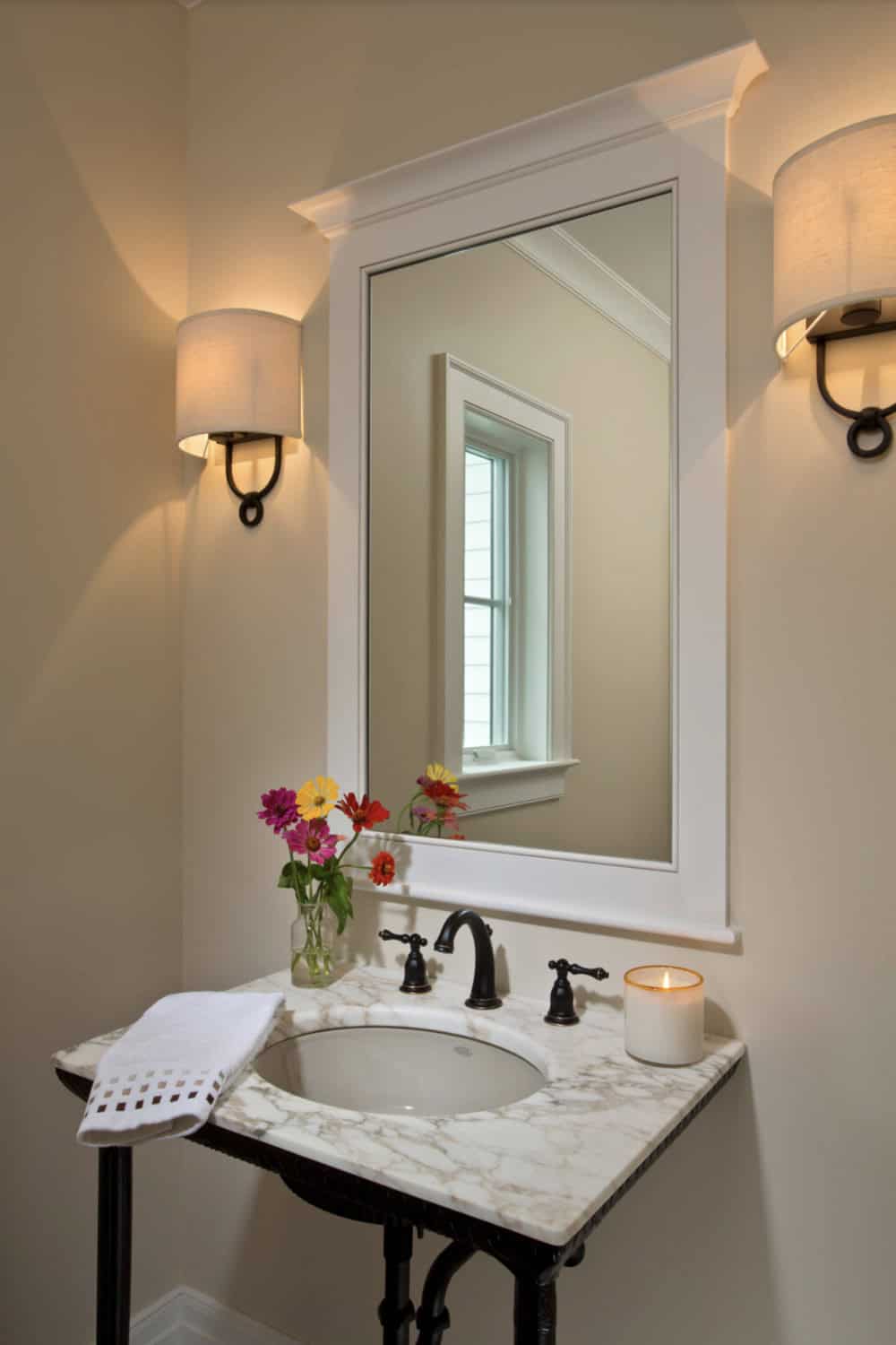 Powder room vanity with marble top, oil-rubbed bronze faucet, and framed mirror
