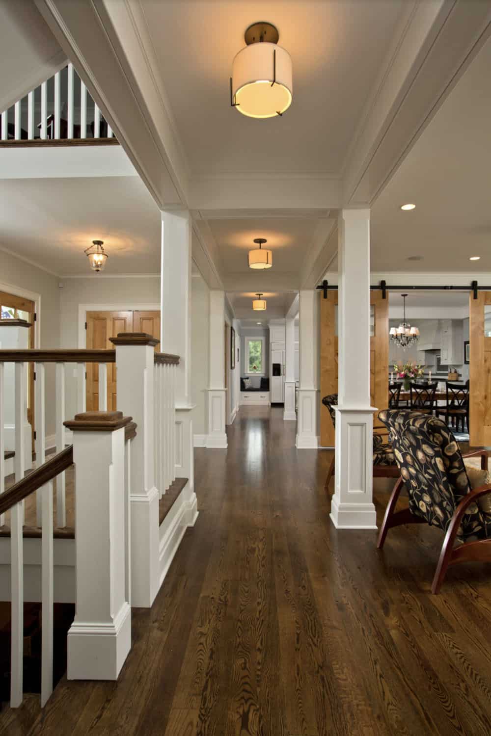 Hallway with dark hardwood floors, white columns, and sliding barn doors