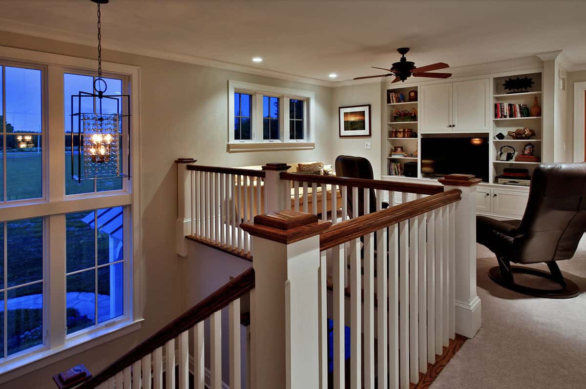 Upper-level landing with built-in bookcases, ceiling fan, and overlooking stairwell