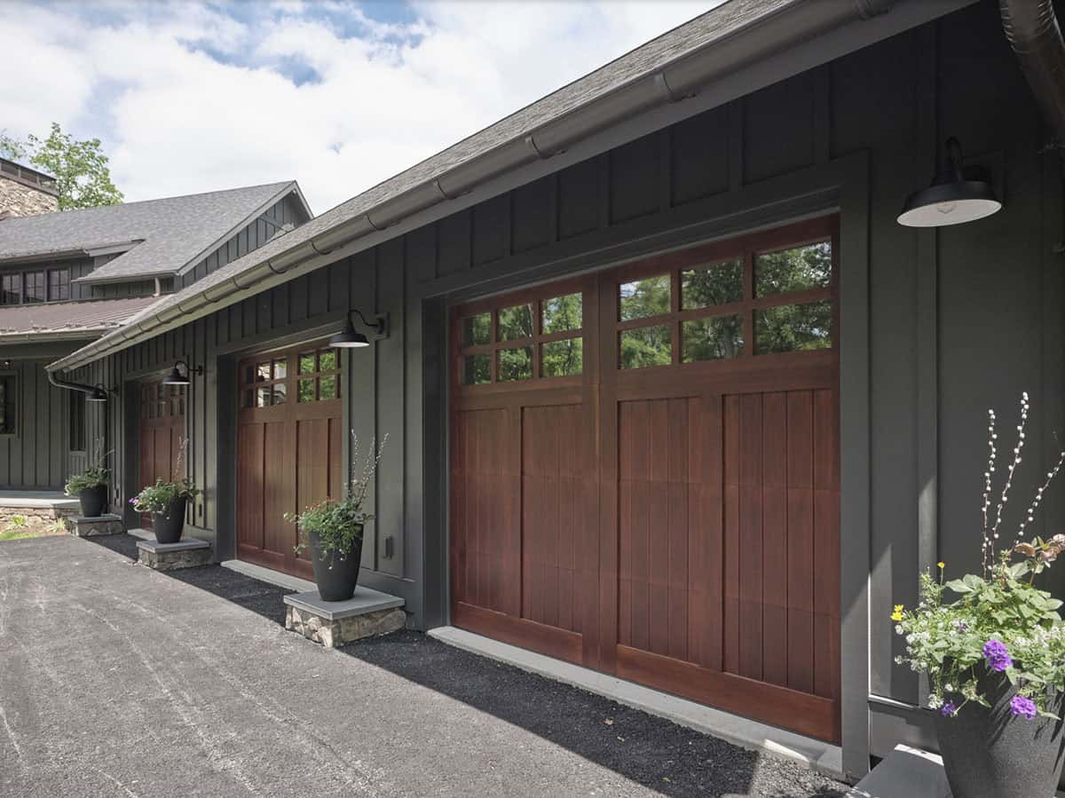 Close-up of wood craftsman garage doors with glass panels and black gooseneck sconces