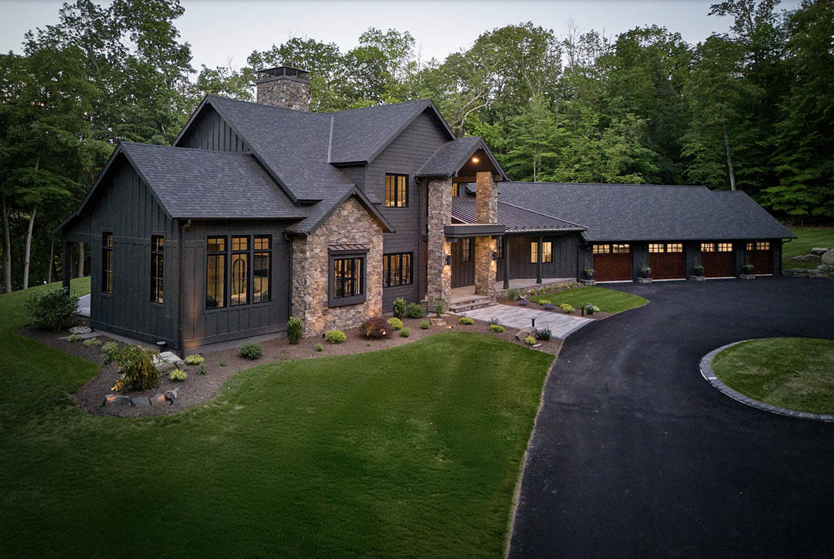 Aerial dusk view of gray craftsman home with stone accents and circular driveway