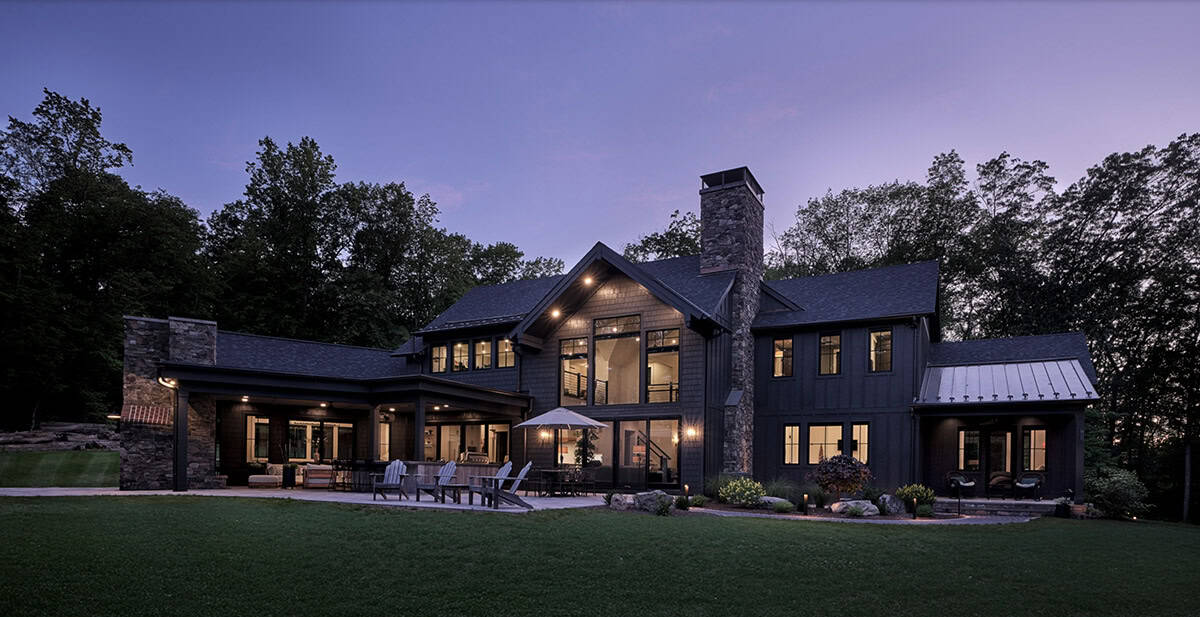 Craftsman home rear exterior at twilight with glowing windows and covered patio