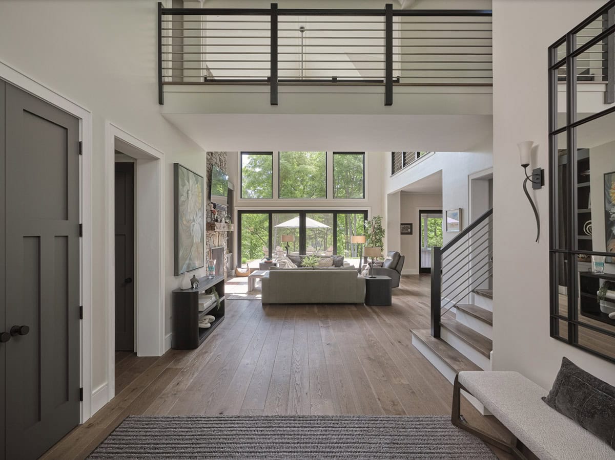 Open foyer looking toward living room with two-story windows, metal railing staircase, and hardwood floors