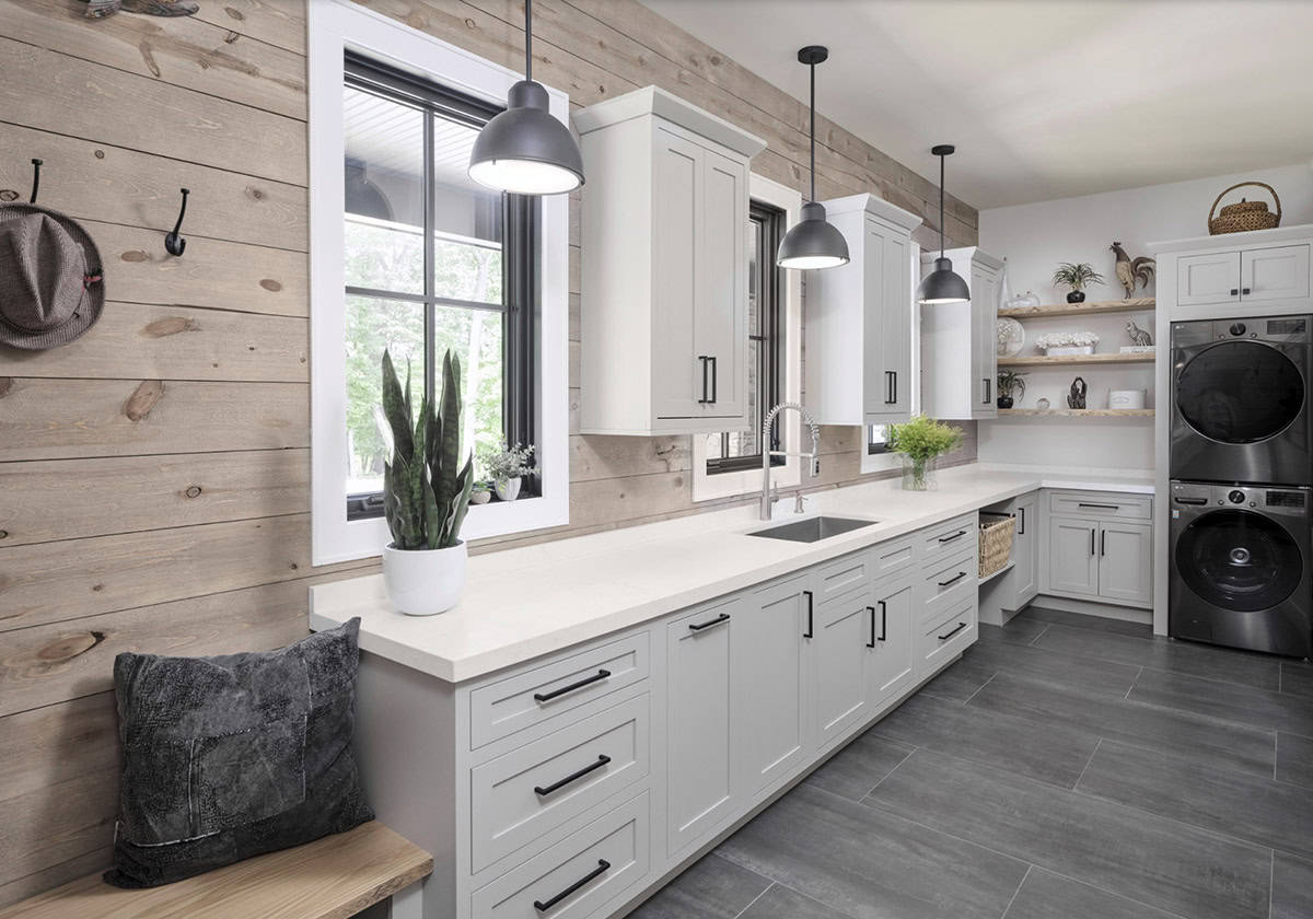 Mudroom and laundry with shiplap walls, white cabinets, stacked washer dryer, and gray tile floor