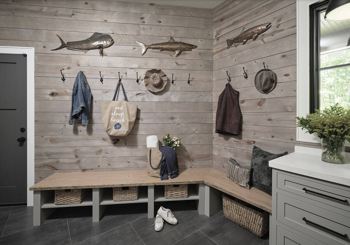 Mudroom with shiplap walls, built-in bench, wicker baskets, coat hooks, and decorative fish sculptures