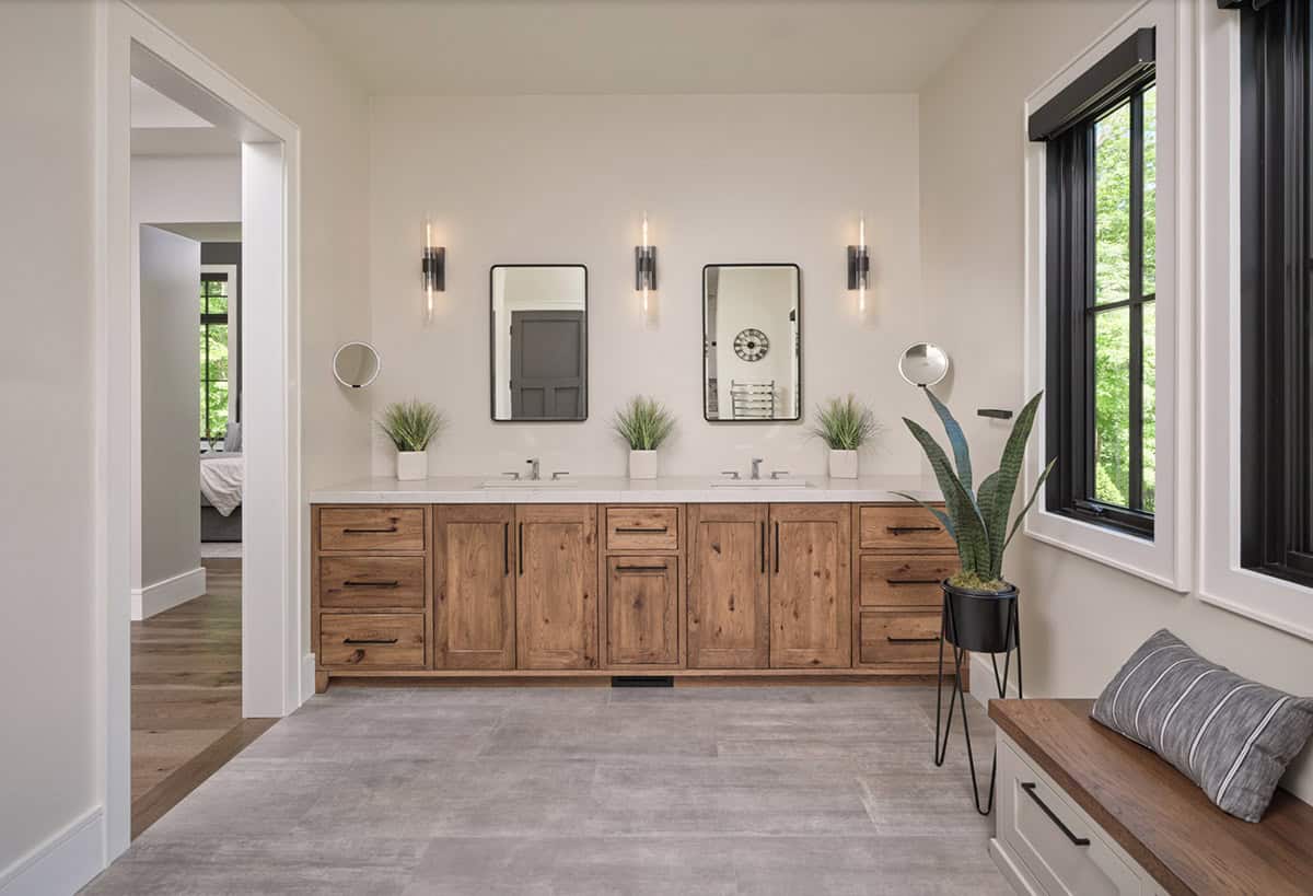 Primary bathroom with double wood vanity, dual mirrors, wall sconces, and gray tile floor