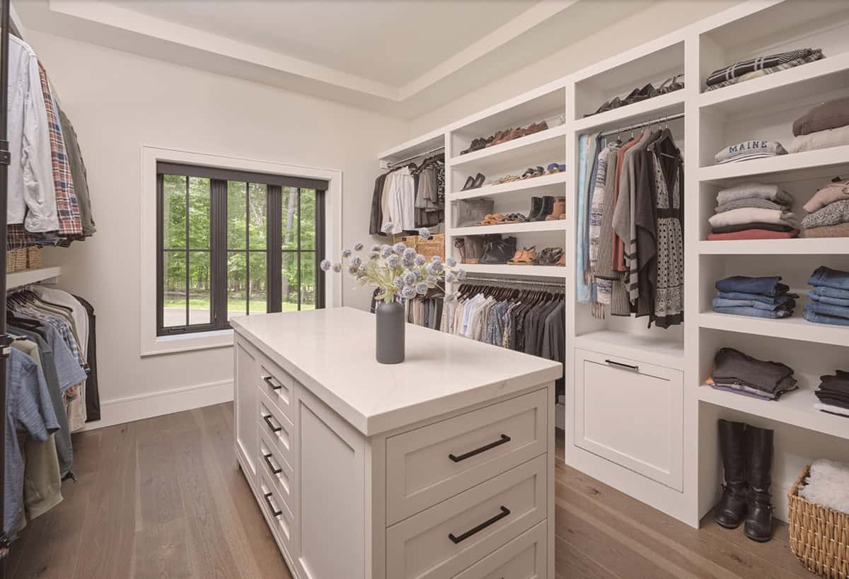 Walk-in closet with center island, open shelving, hanging storage, and black window
