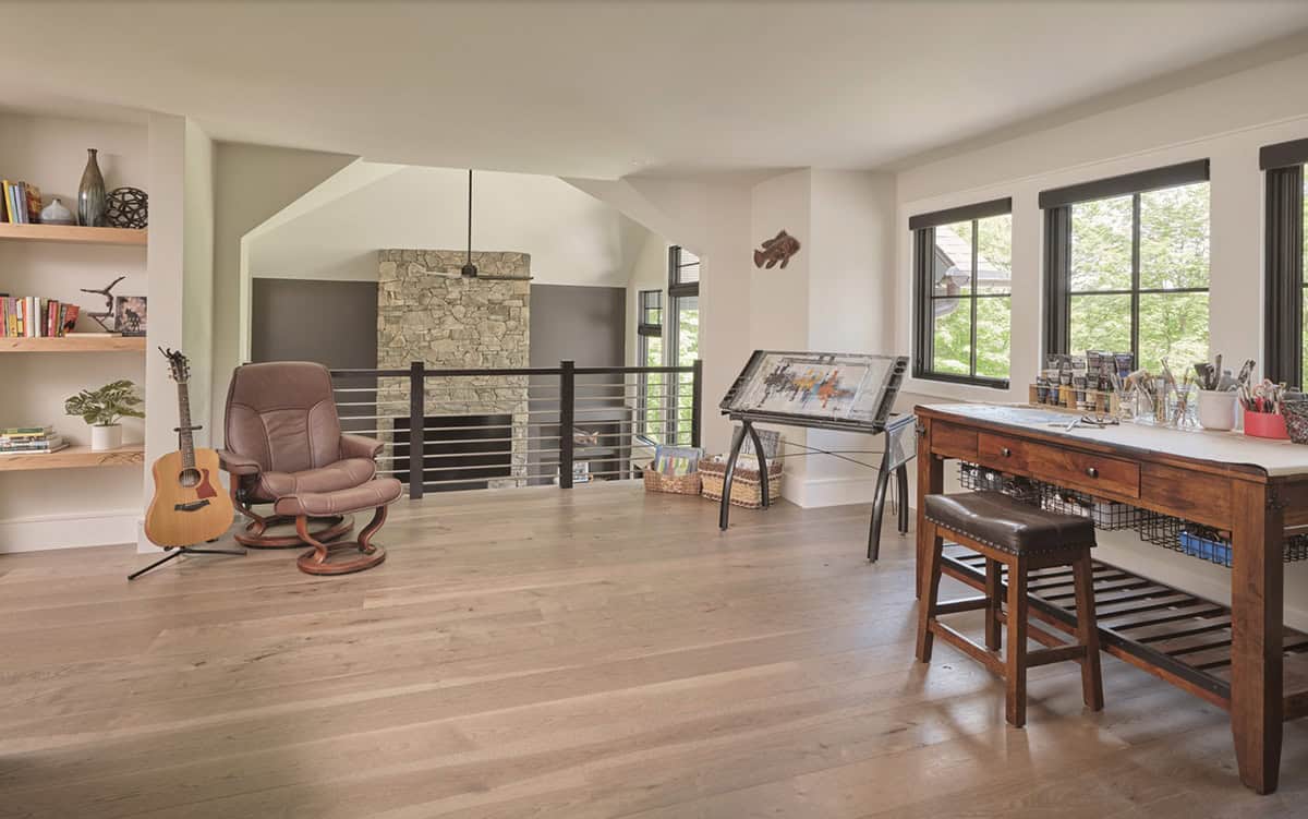 Open loft art studio with drafting table, guitar, leather chair, and built-in shelving