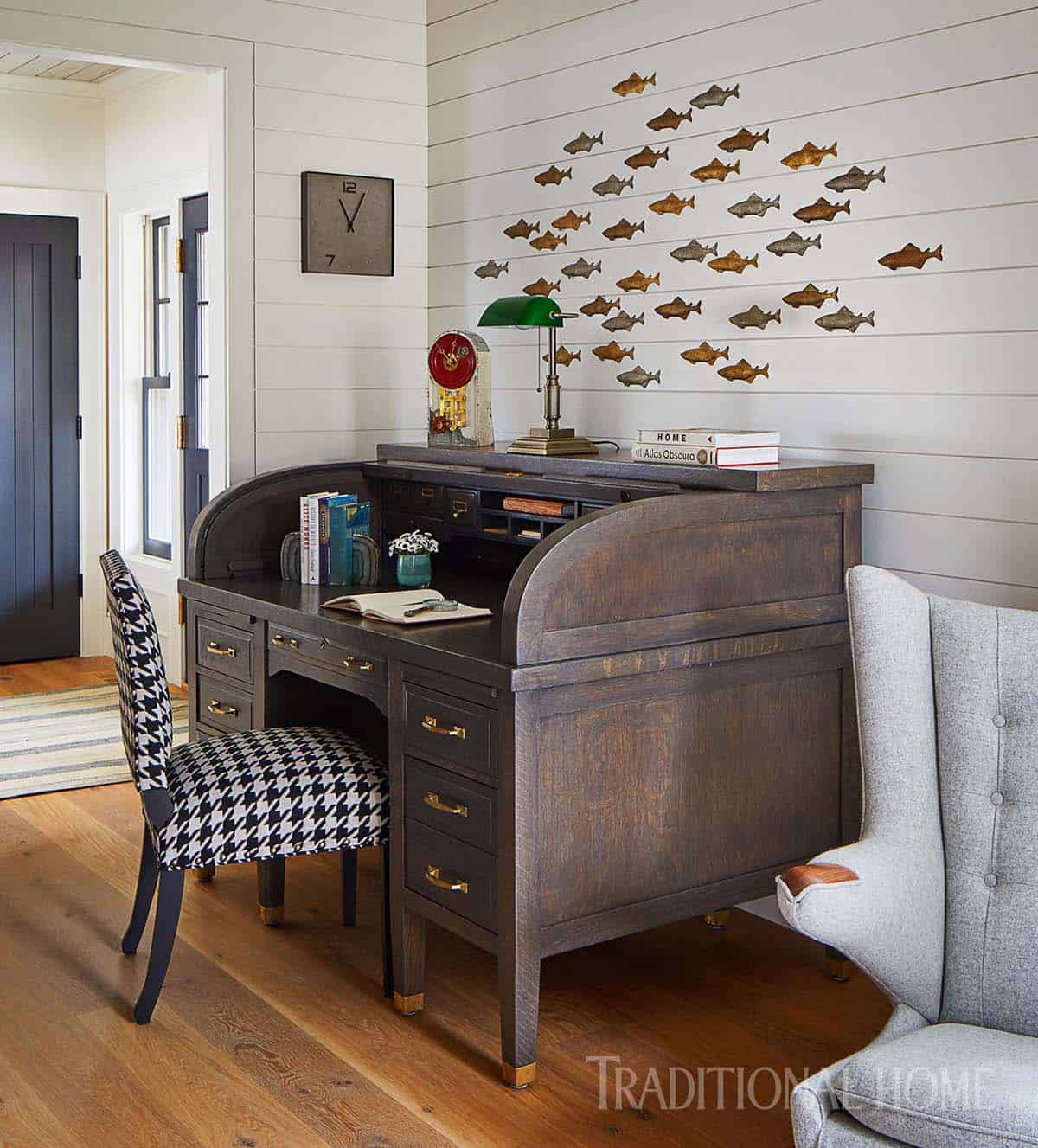 Vintage roll-top desk with houndstooth chair and school of fish wall art on shiplap wall