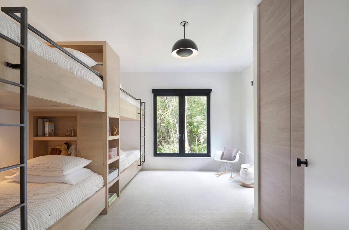 Modern farmhouse kids bedroom with custom built-in wood bunk beds, blackened steel ladders and woodland views in Vermont