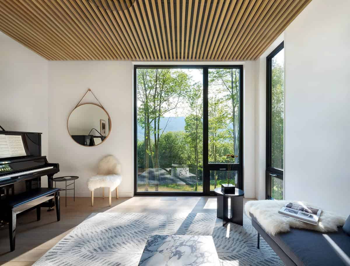 Modern farmhouse sitting room with wood slat ceiling, grand piano and Green Mountain views in Vermont