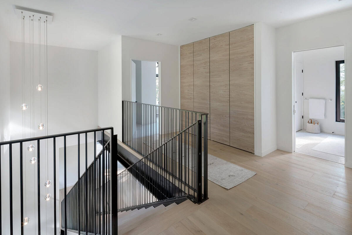 Modern farmhouse upper hallway with black steel staircase, wood veneer cabinetry and pendant lighting in Vermont