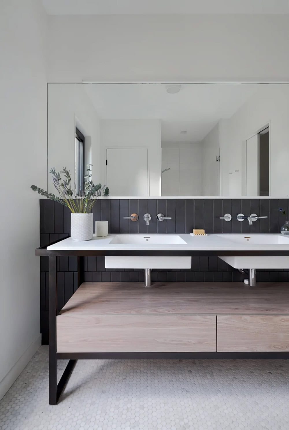 Modern farmhouse bathroom double vanity with blackened steel frame, wood cabinetry and dark tile backsplash