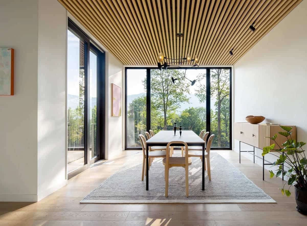 Modern farmhouse dining room with wood slat ceiling, floor-to-ceiling European windows and Green Mountain views in Vermont
