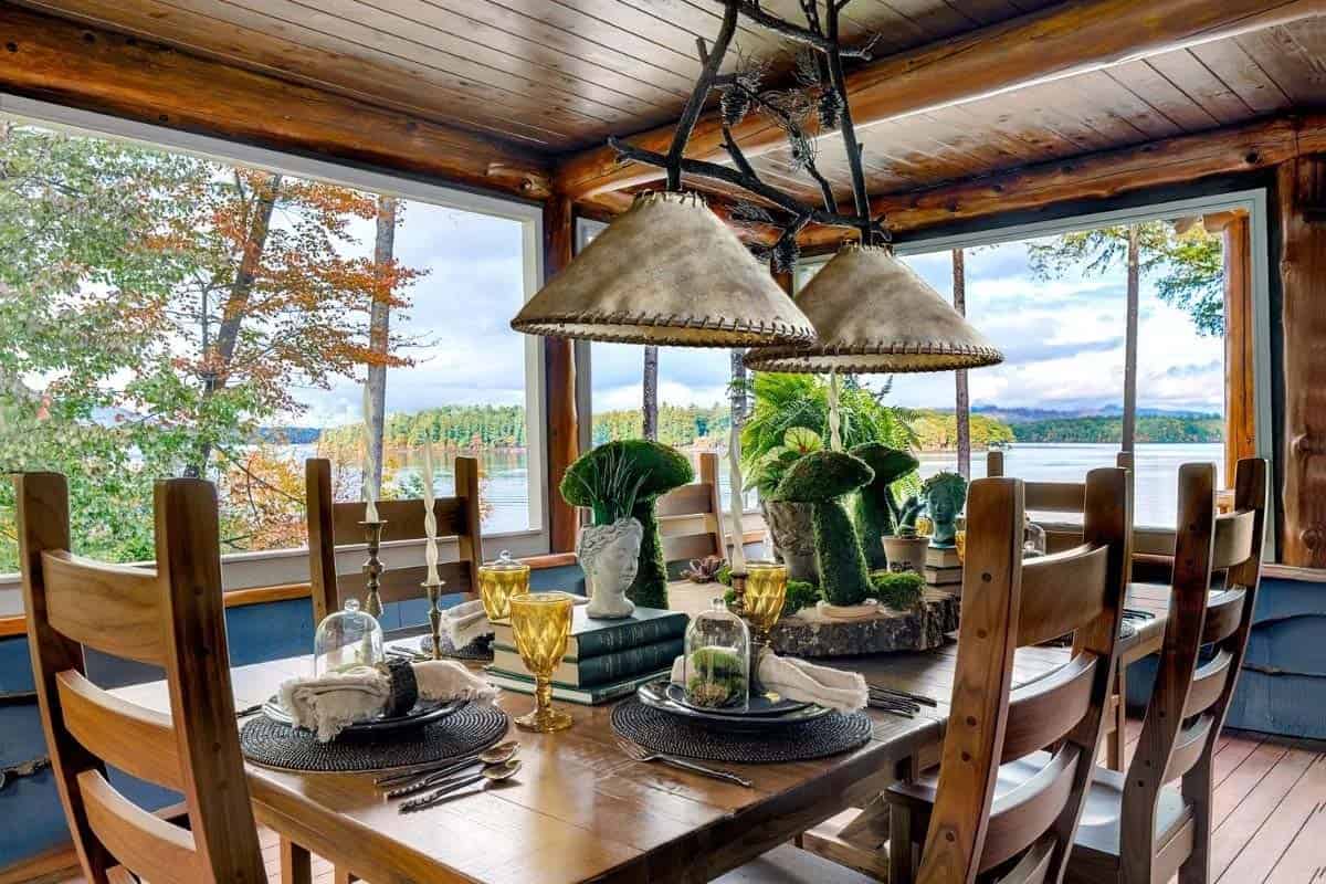 Lake-view dining area with twig chandelier, leather shade pendants, and nature-themed table setting