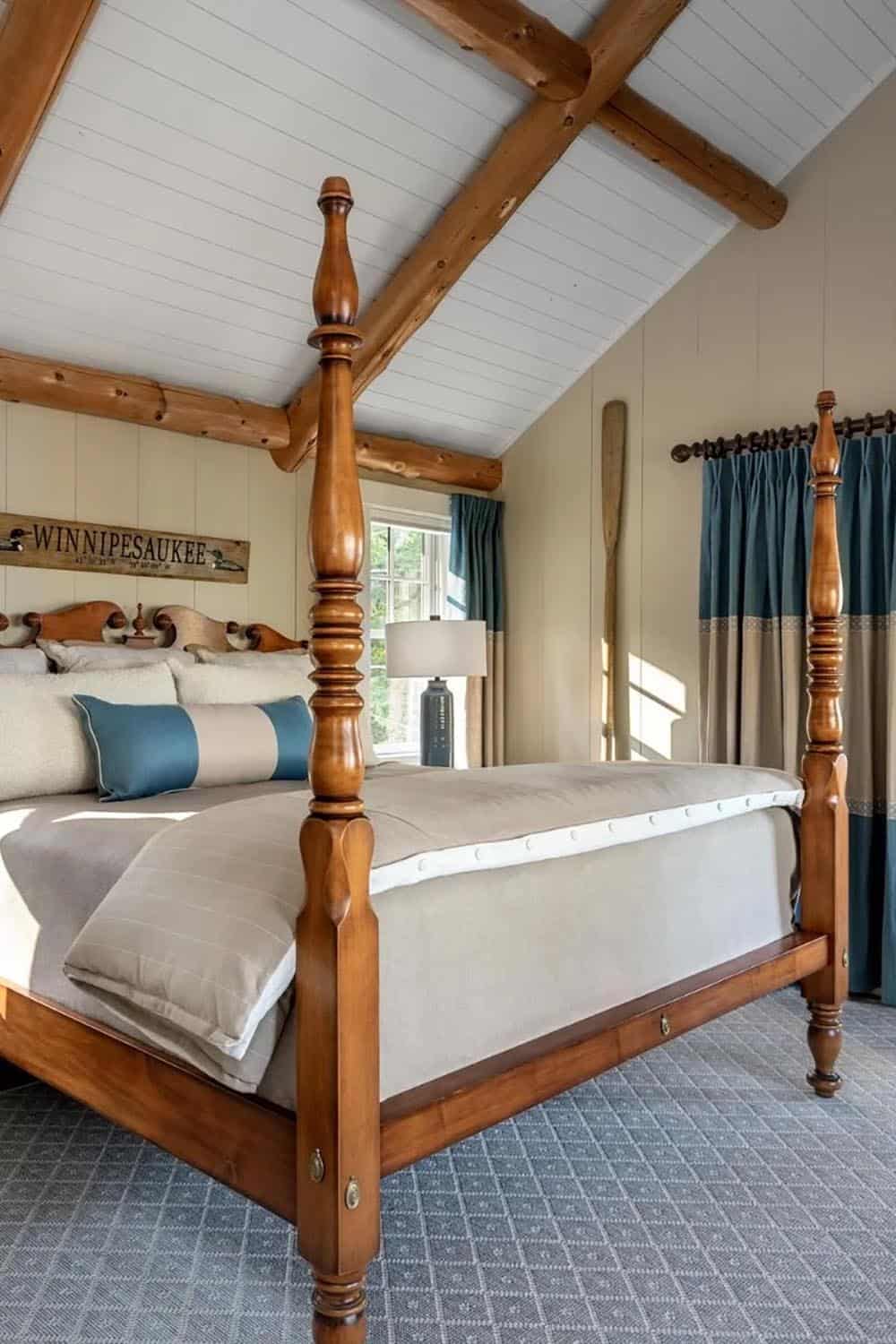 Lake house bedroom with four-poster cherry wood bed, teal curtains, log ceiling beams, and Winnipesaukee sign