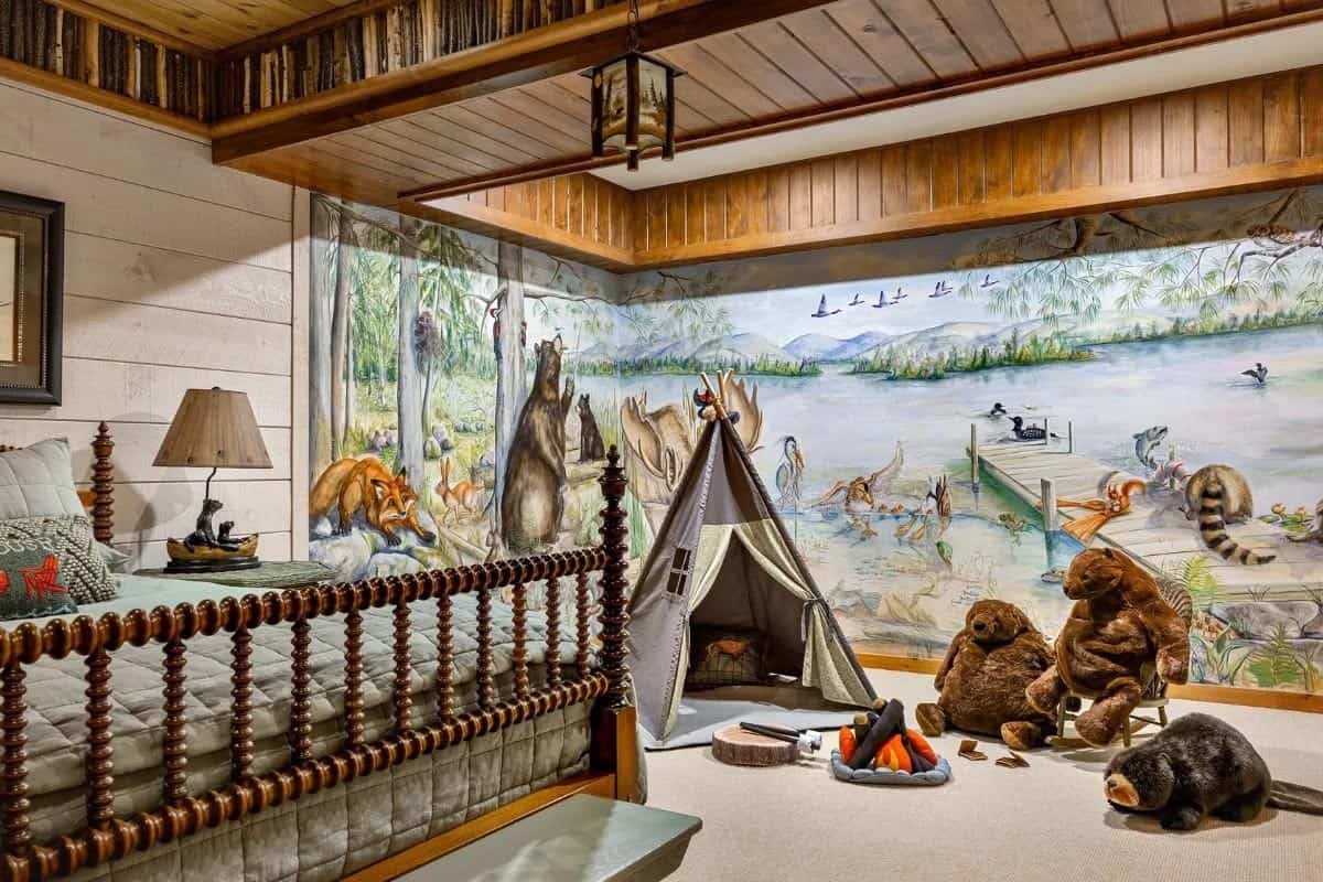 Children's bedroom with hand-painted woodland lake mural, spool bed, play teepee, and stuffed animals