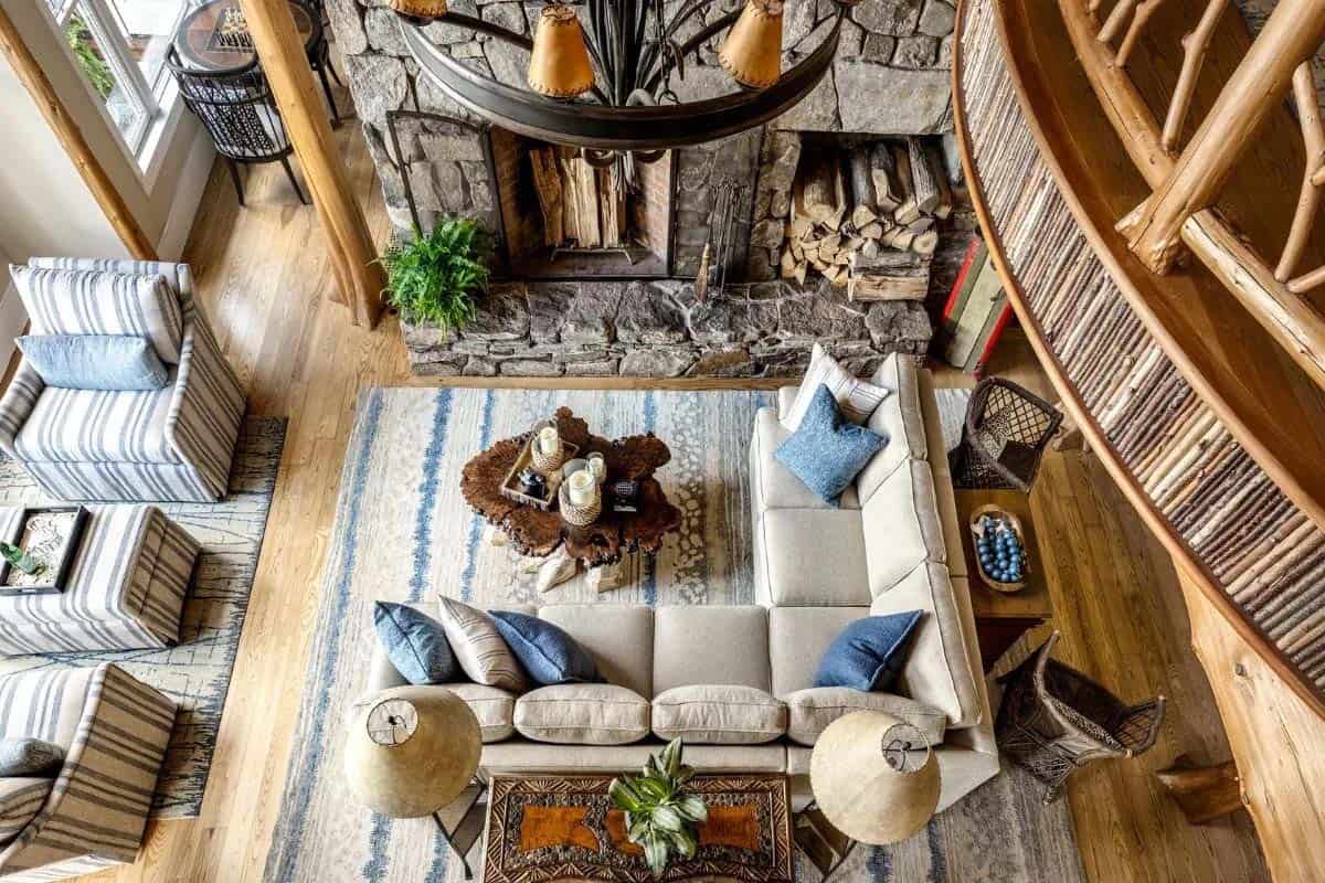 Aerial view of great room with stone fireplace, sectional sofa, blue accent pillows, and live-edge coffee table