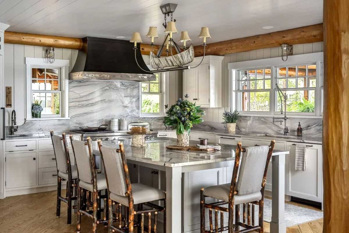 Bright white kitchen with marble slab backsplash, hickory bar stools, log beams, and canoe-shaped chandelier