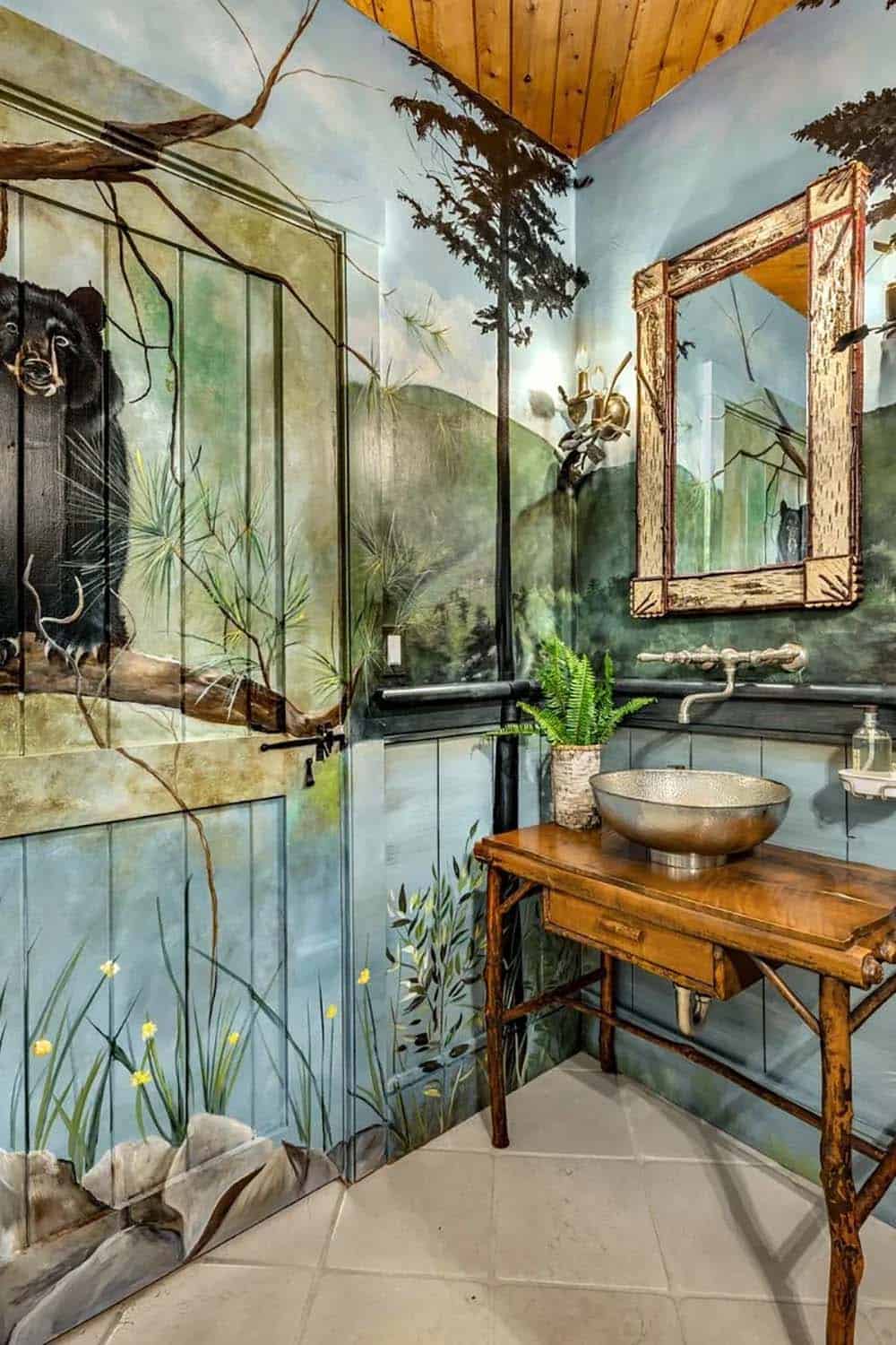 Powder room with floor-to-ceiling forest mural, hammered metal vessel sink, and birch-framed mirror