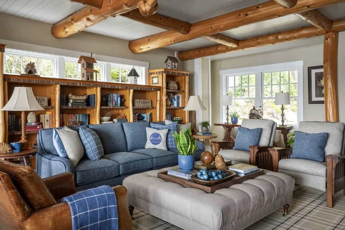 Casual living room with blue sofa, log beam ceiling, built-in bookshelves, and leather armchair
