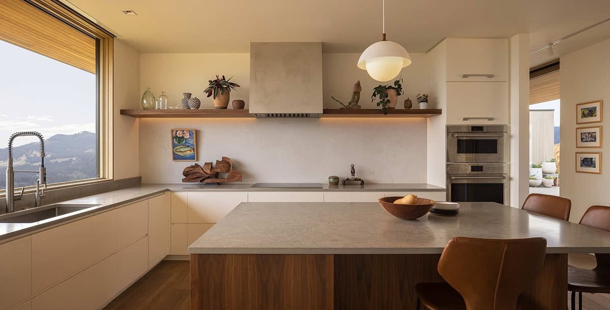 Modern kitchen with stone countertops, walnut island, open shelving, and mountain views