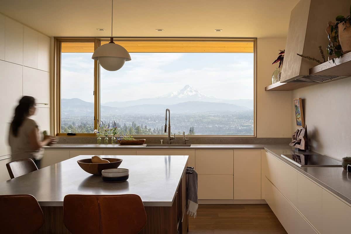 Kitchen sink framed by a large picture window with a dramatic snow-capped mountain view