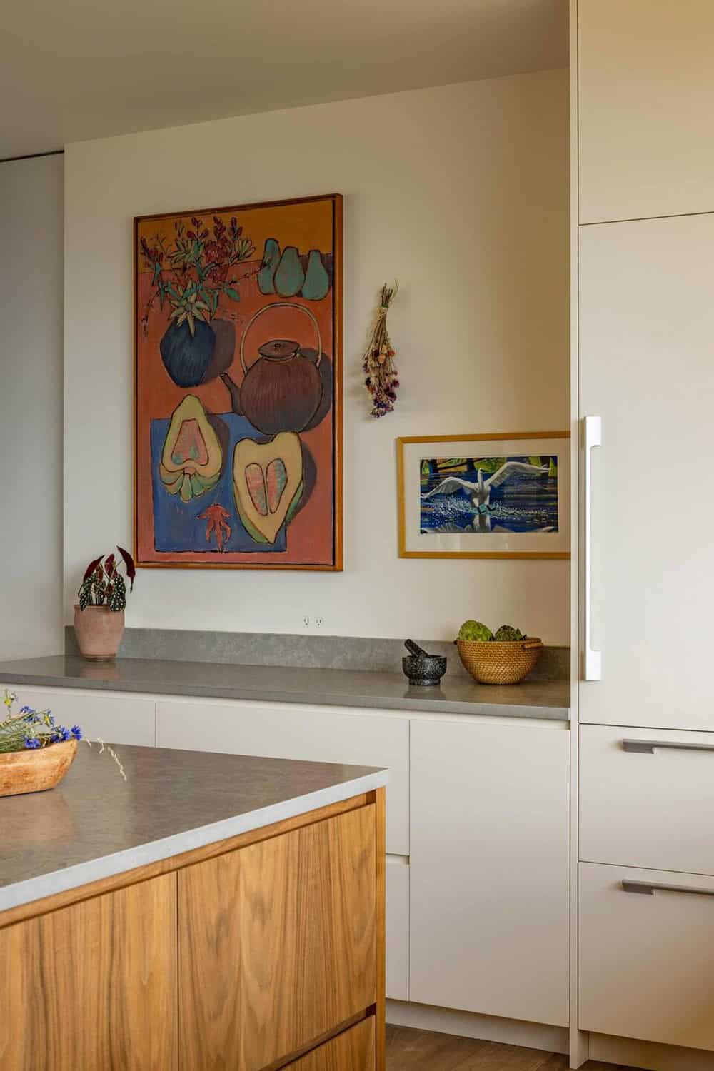 Kitchen corner with colorful still-life painting, stone counters, and walnut island cabinetry