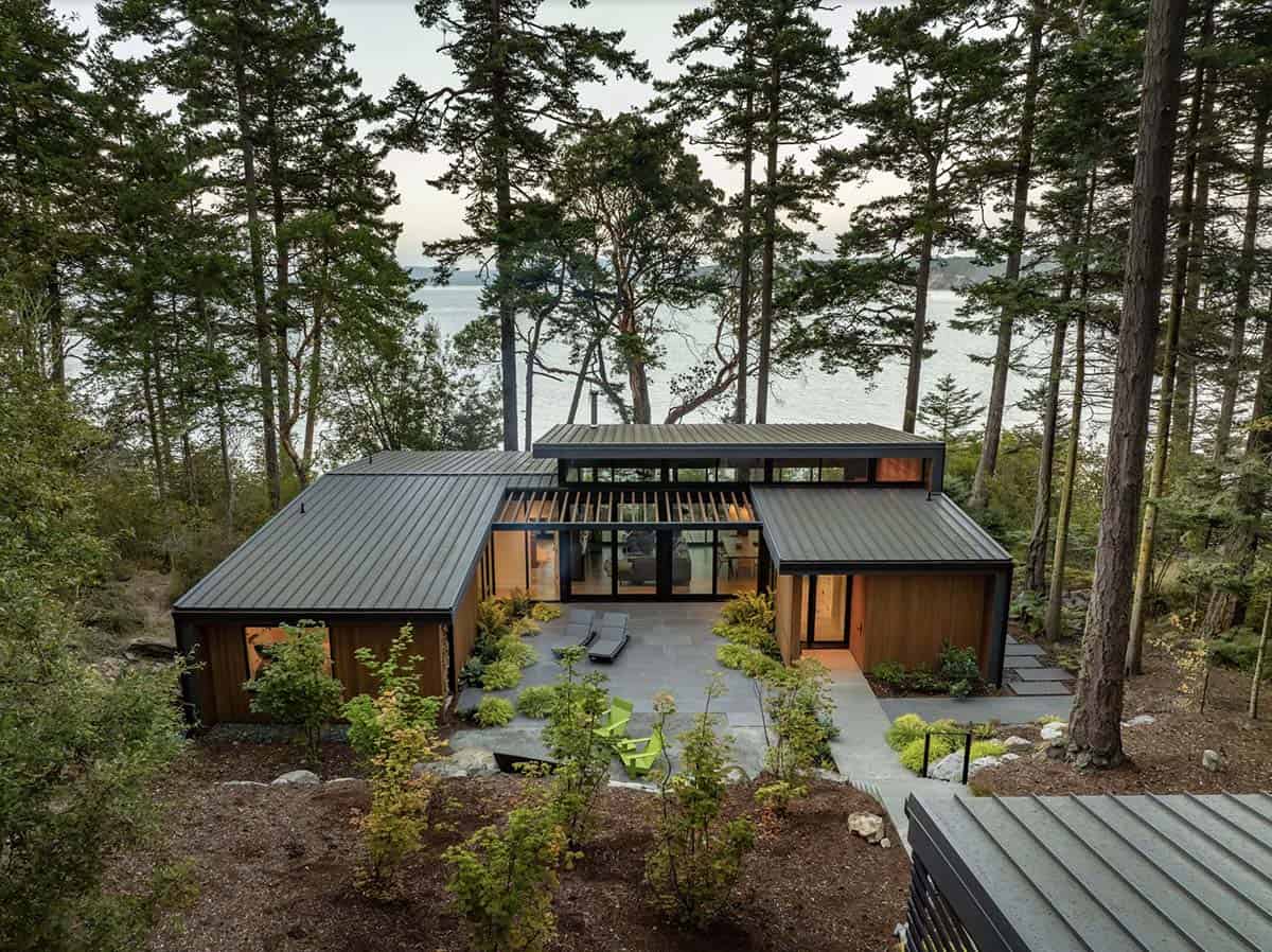 Aerial view of single-story modern residence nestled among tall pines with standing-seam metal roof and central courtyard