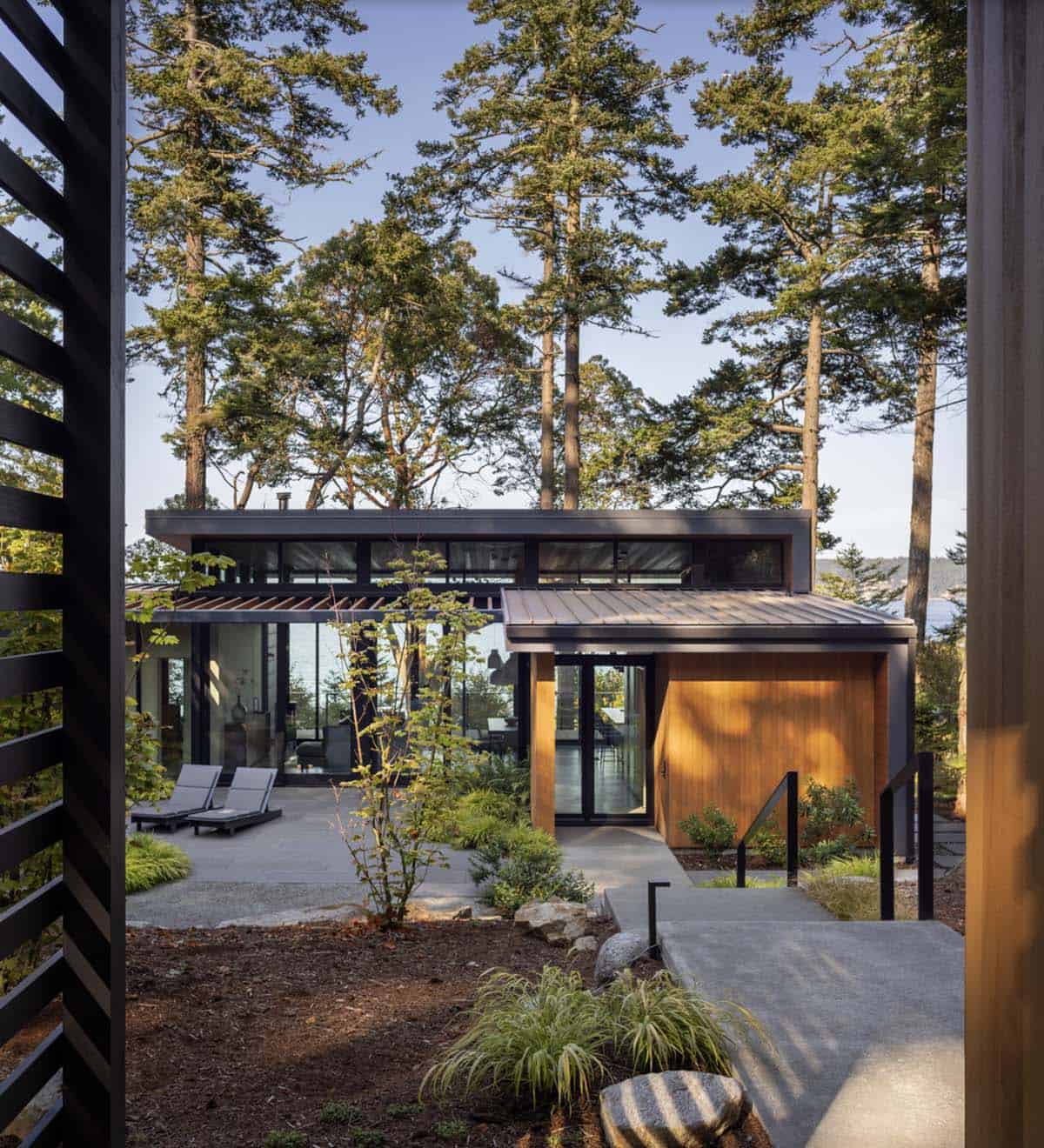 Entry courtyard of cedar and glass home viewed through black horizontal privacy screen