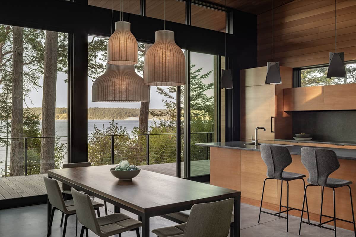 Open-plan dining area with woven pendant lights, wood dining table, and panoramic water views