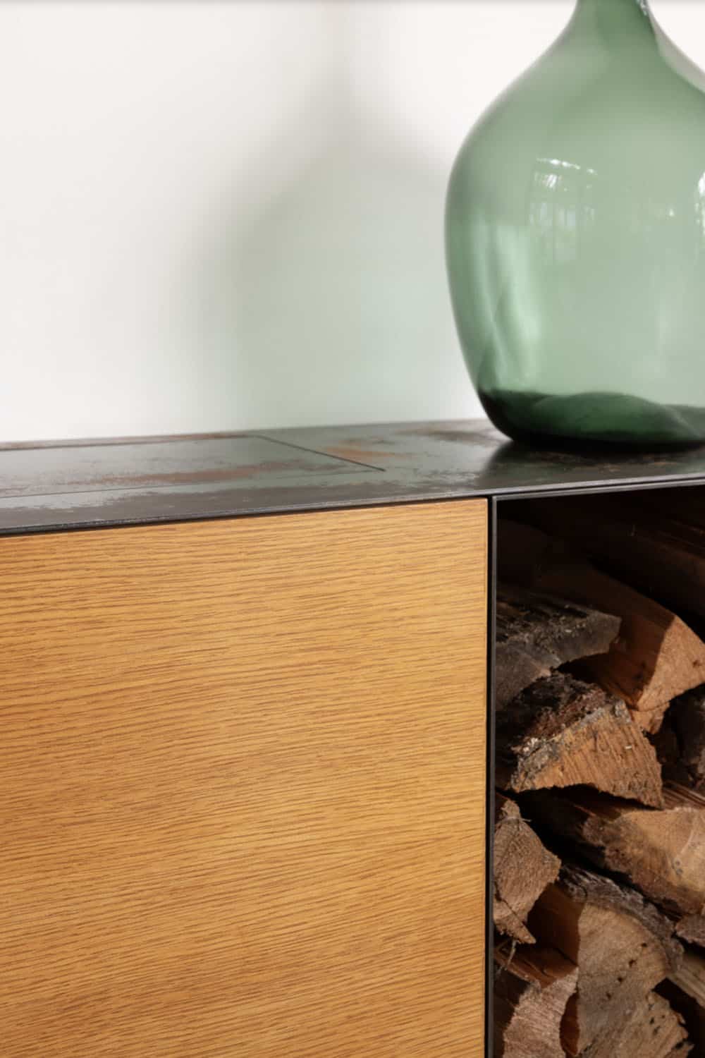 Close-up detail of oak wood cabinet with dark steel top and open firewood storage compartment