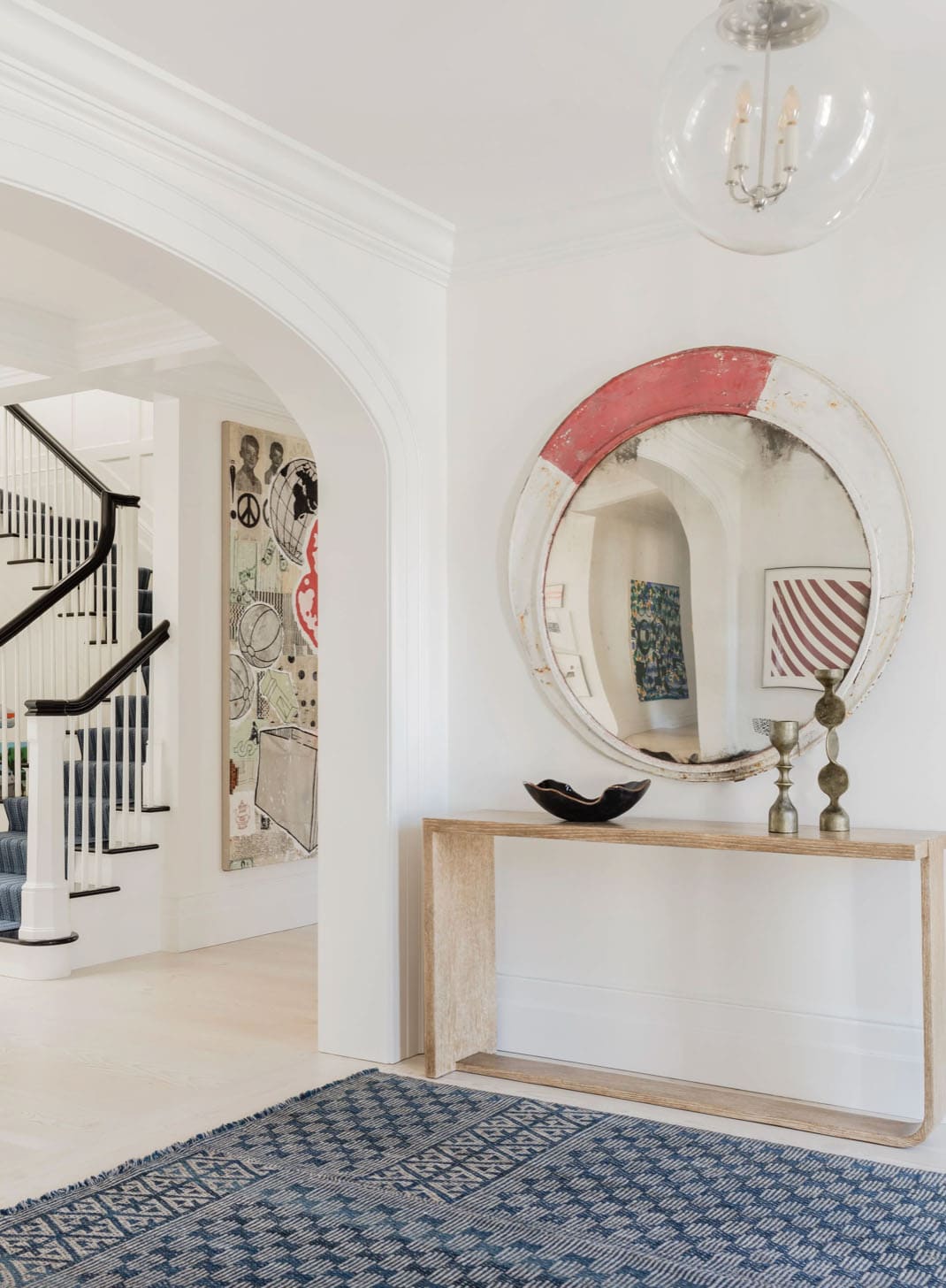 Entryway with distressed round mirror, oak console table, and bold pop-art painting