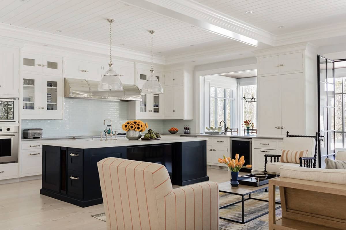 White kitchen with navy island, glass pendant lights, and beadboard ceiling