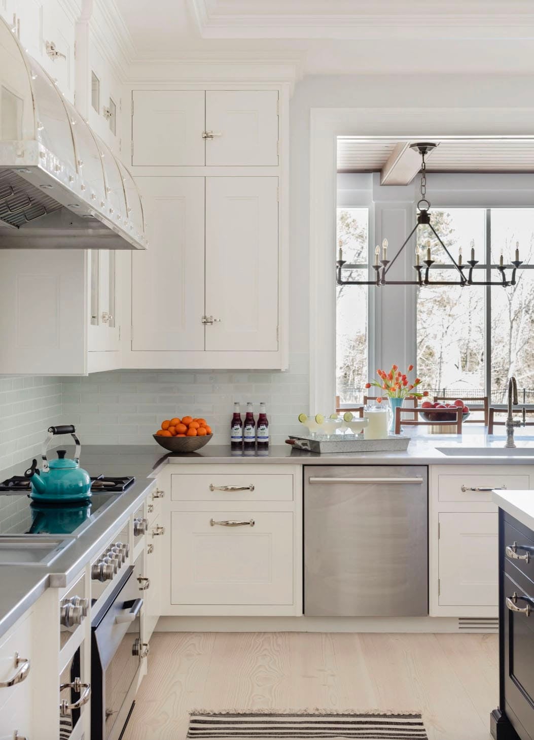 Kitchen cooking zone with stainless range hood, subway tile backsplash, and garden window