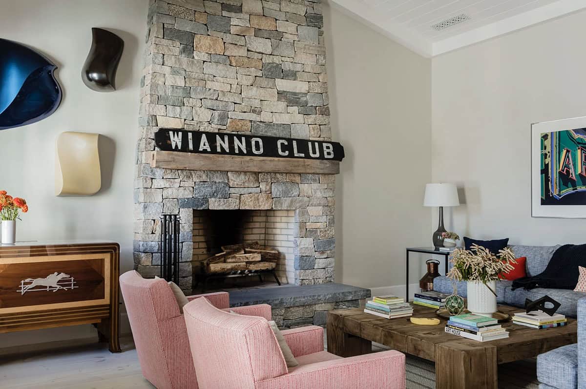 Stone fireplace with Wianno Club sign, pink armchairs, and rustic wood coffee table