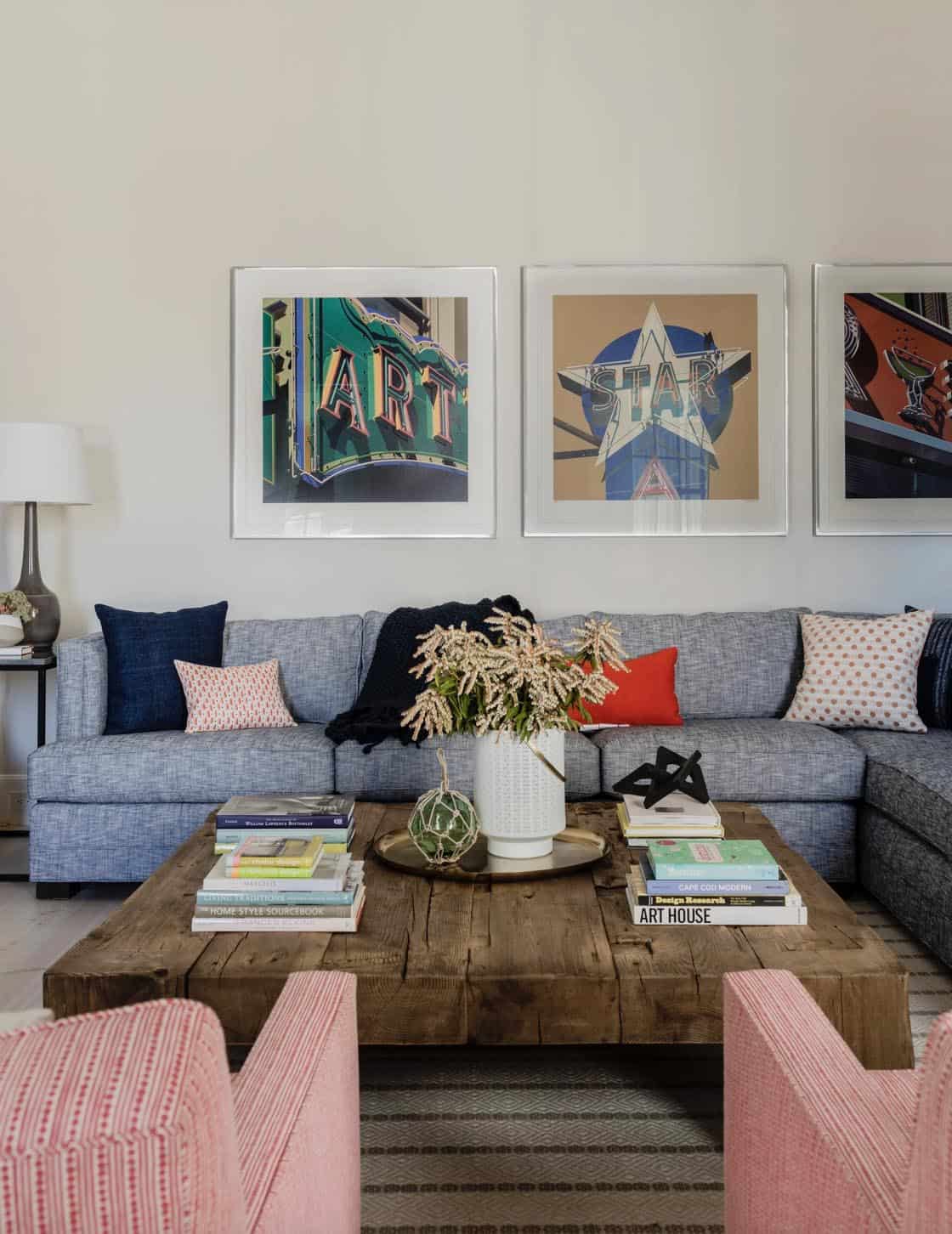 Living room with blue-gray sectional, reclaimed wood coffee table, and neon sign art triptych