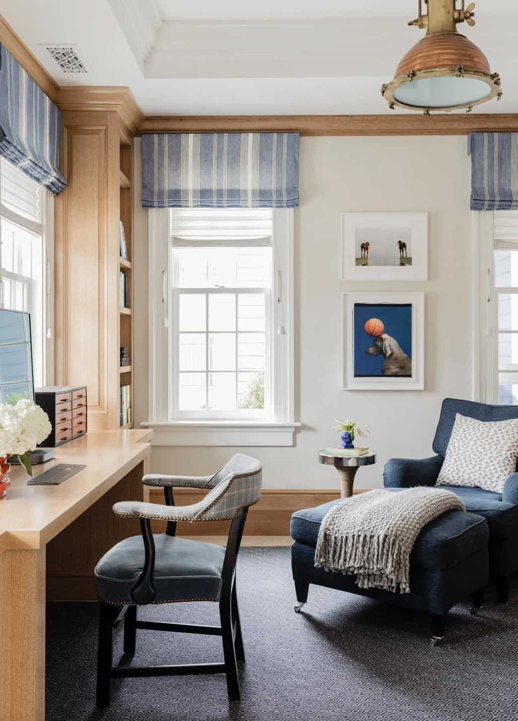 Home office with built-in oak desk, blue navy reading chair, and brass industrial pendant