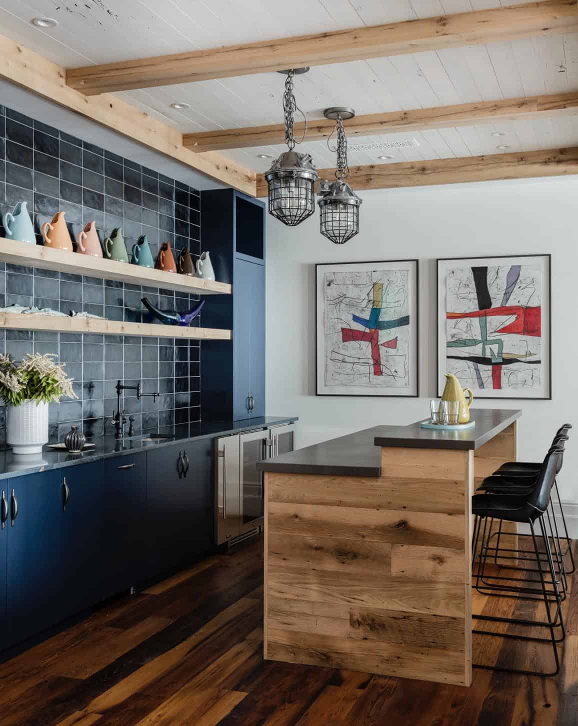 Lower level wet bar with navy cabinets, dark square tile backsplash, reclaimed wood island, and industrial cage pendants
