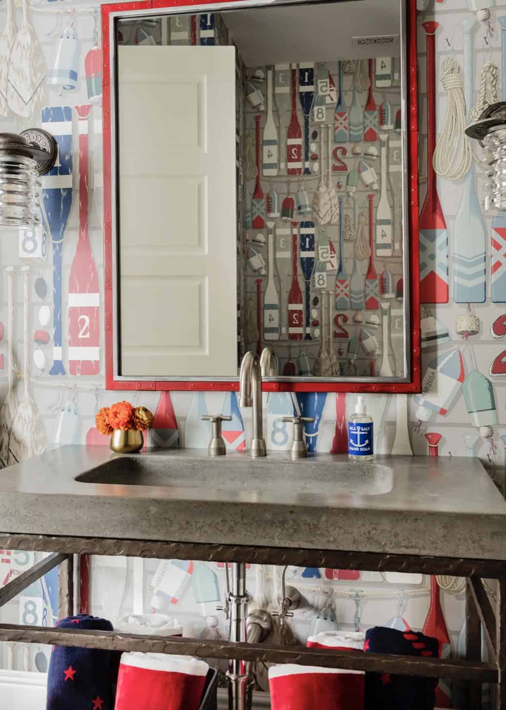 Kids' bathroom with nautical oar wallpaper, concrete sink, red-framed mirror, and industrial sconces
