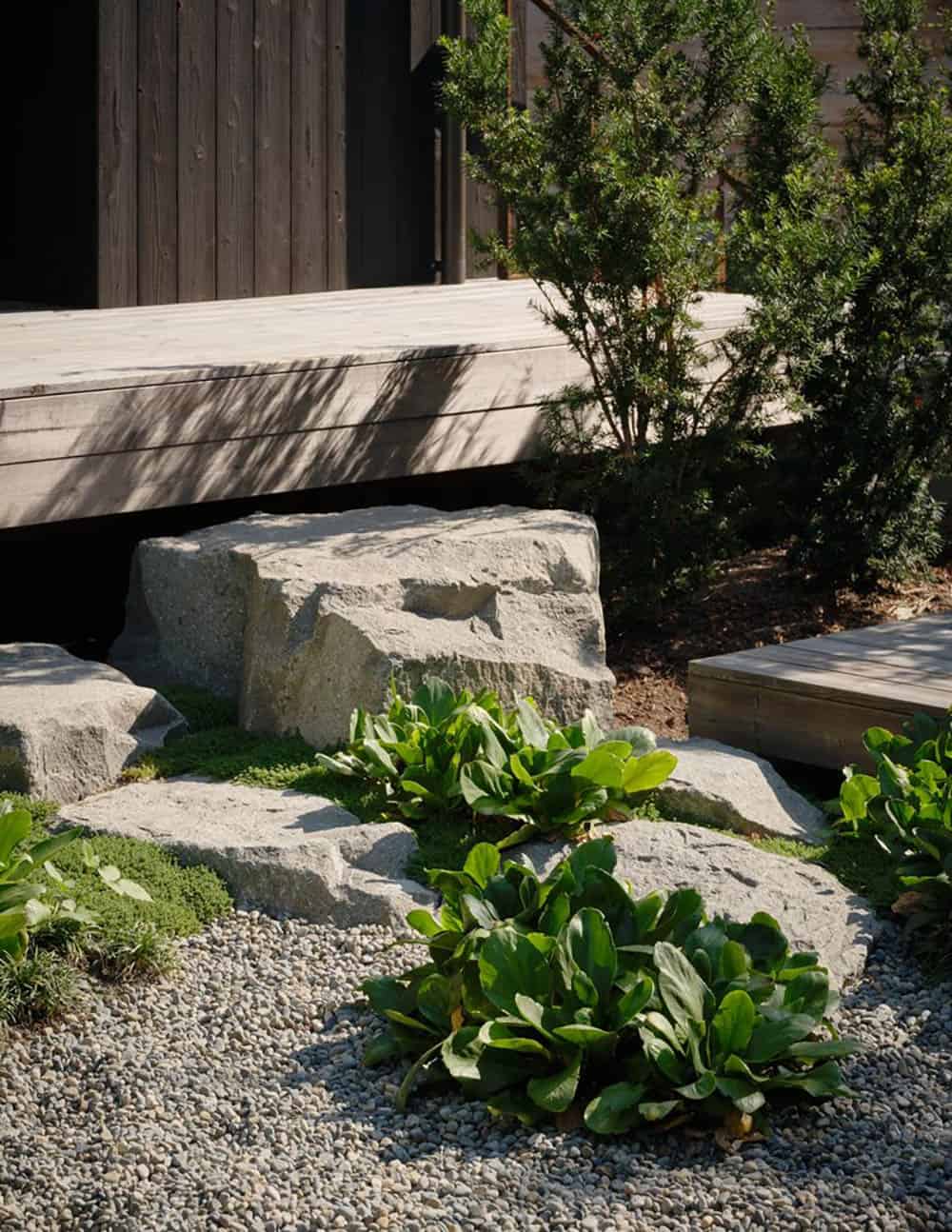 Granite boulders and low plantings in gravel garden beneath floating deck