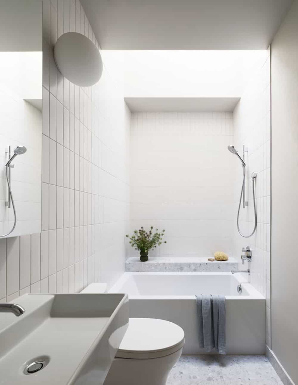 All-white bathroom with skylight, soaking tub alcove, and vertical tile walls
