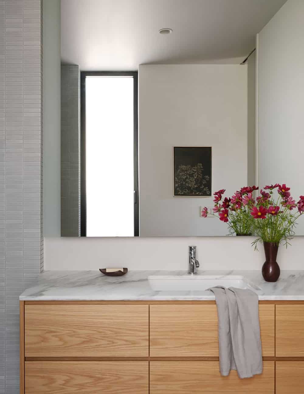 Primary bathroom vanity with white oak cabinetry, marble countertop, and pink flower arrangement