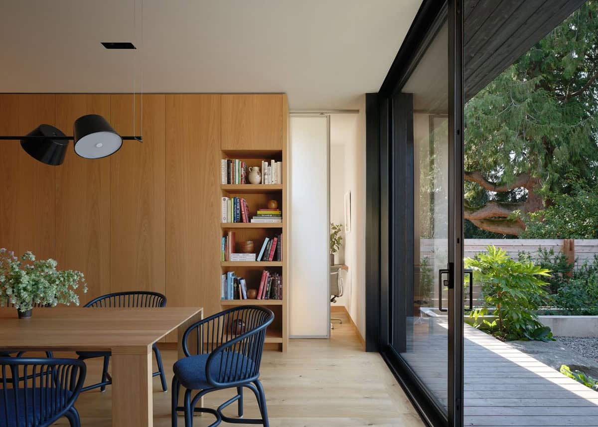 Dining area with oak table and navy chairs opening via sliding glass door to garden deck