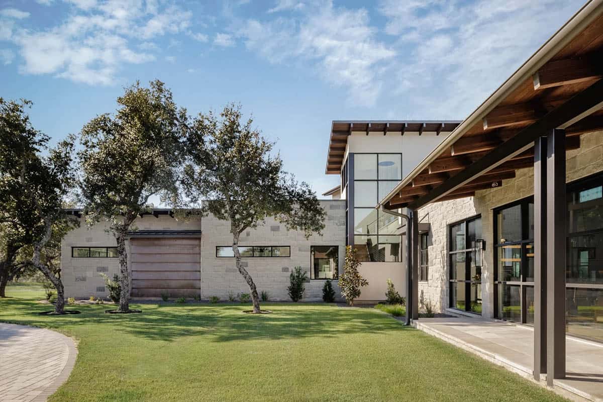 Side view of Hill Country ranch home with wood beam porch ceiling and lush lawn