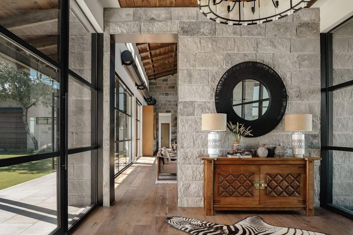 Entryway with limestone walls, steel frame windows, wood console and zebra rug