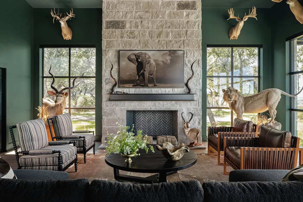 Trophy room with deep green walls, stone fireplace and safari-inspired decor